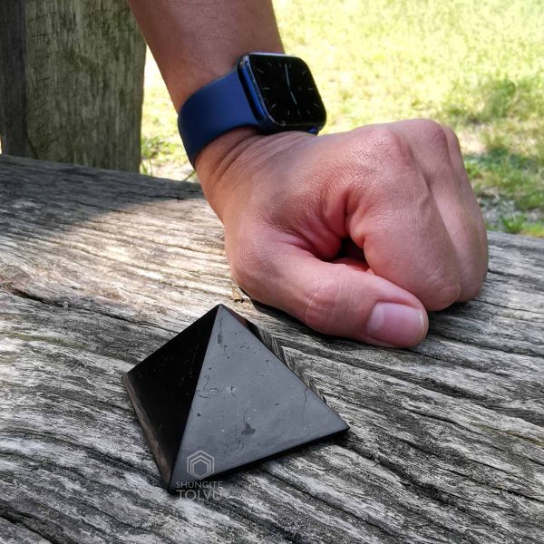 shungite stone pyramid and hand